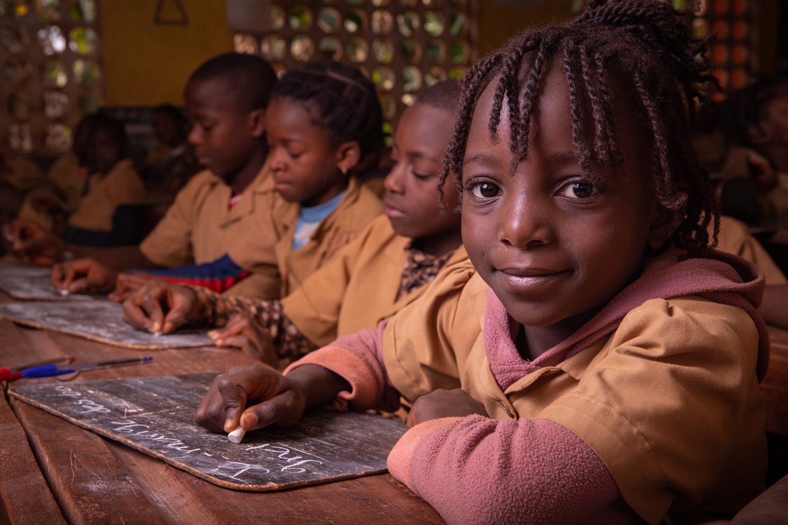 students-in-a-school-in-africa-take-the-lesson-and-2026-03-19-22-09-31-utc (1) Nena somrient escrivint en una pissarra a l'escola a Gàmbia
